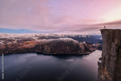 Man hiker standing on the famous Preikestolen over the Lysefjord, beautiful colors at sunset, Ryfylke, Rogaland, Norway photo