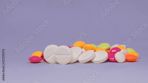 Various multicolor pills lying on purple background