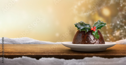 Christmas banner background of a traditional Christmas pudding on the right with a sprig of holly on top with a golden blurred background. photo