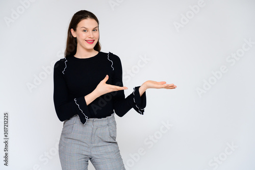 Concept adult girl on a white background. A photo of a pretty brunette girl in gray trousers and a black sweater smiles and shows different emotions in different poses right in front of the camera.