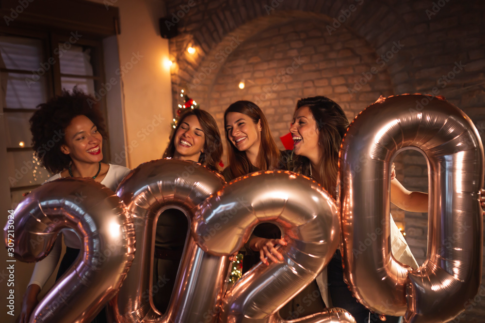 Girlfriends at New Year party holding balloons 2020