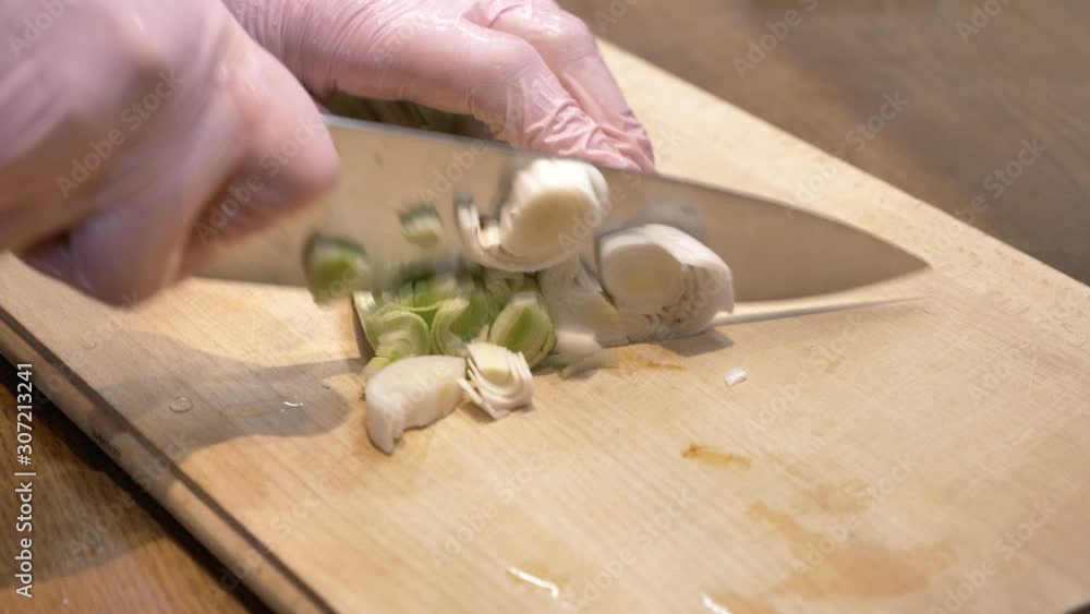 The chef cuts the leeks close up slow wooden board hand in gloves The chef cuts the leeks close up slow wooden board hand in gloves