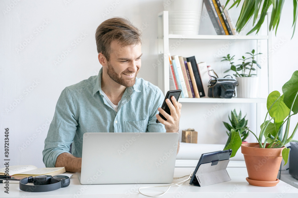 Smiling man using smartphone at desk in office