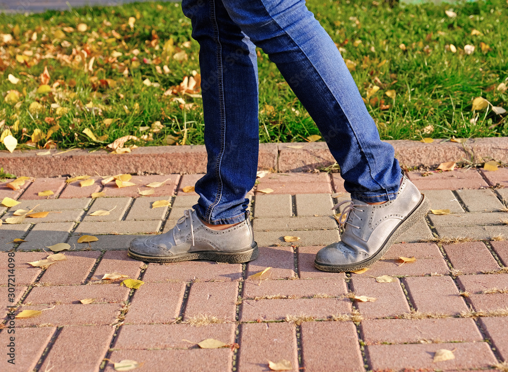 Close up of a woman legs walking in an autumn park on sidewalk in sunny day; healthy lifestyle, activity concept Close up of a woman legs walking in an autumn park on sidewalk in sunny day; healthy lifestyle, activity concept
