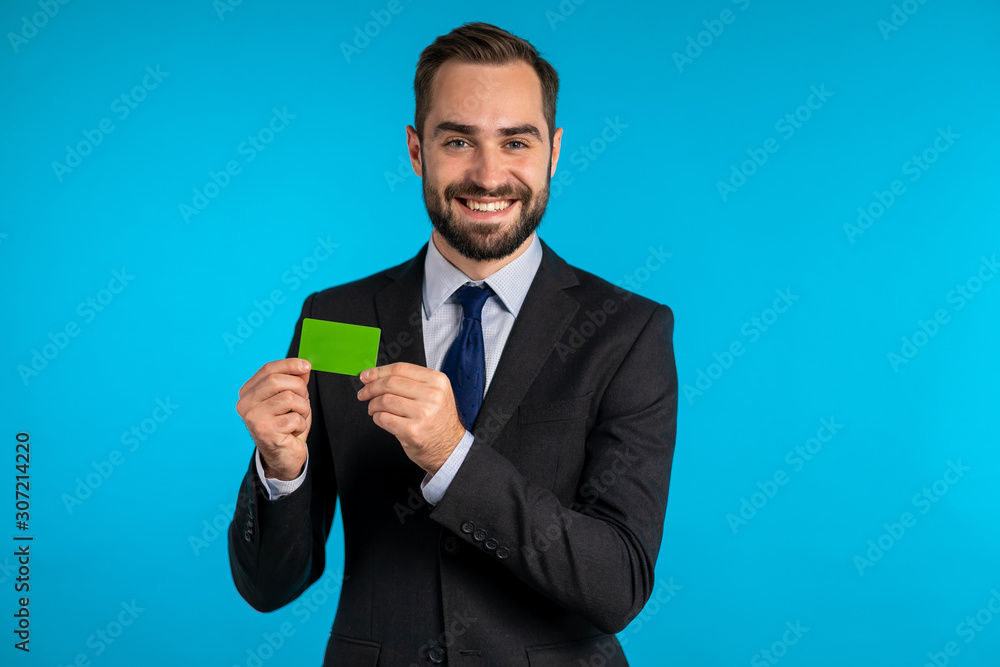 Successful man in business suit showing unlimited green credit card on blue studio background. Professional male manager. Successful man in business suit showing unlimited green credit card on blue studio background. Professional male manager.