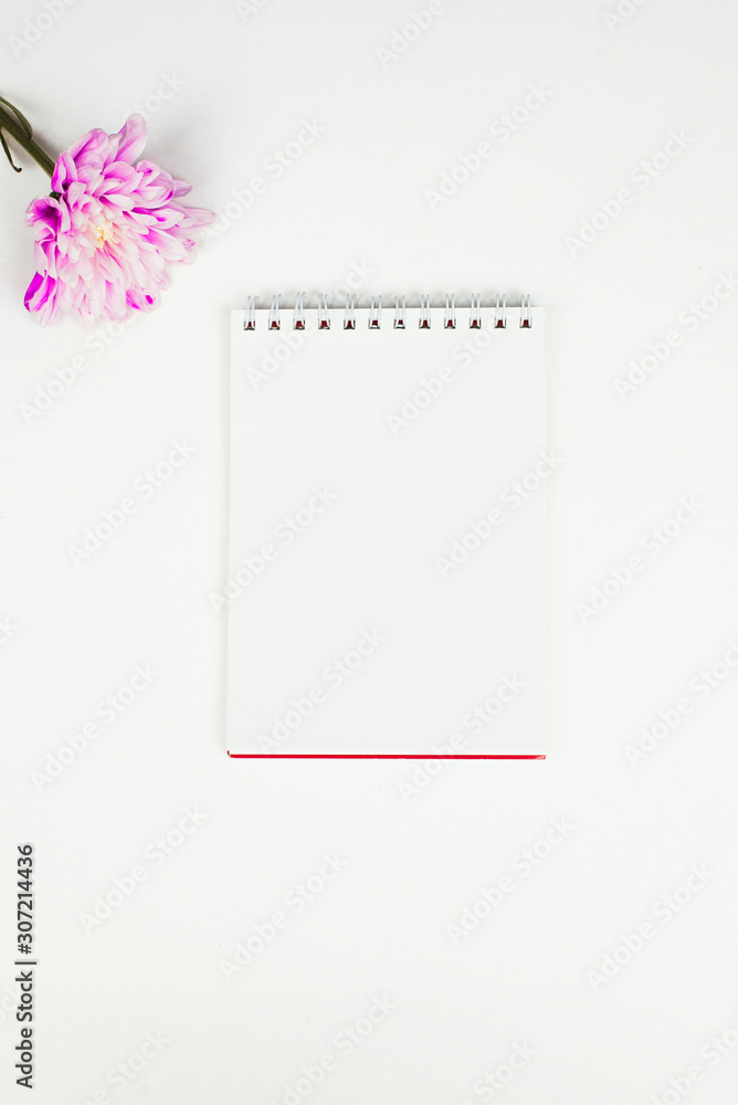 Blank notebook with pink flower on a white background. Top view of little plant with flowers on blank notebook on white fabric workspace background. Copyspace, mockup Blank notebook with pink flower on a white background. Top view of little plant with flowers on blank notebook on white fabric workspace background. Copyspace, mockup