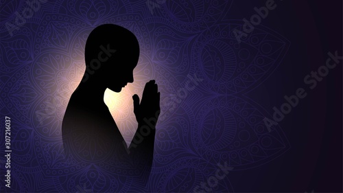 Black silhouette of a praying person, a Buddhist on a background of bright light, a man meditating