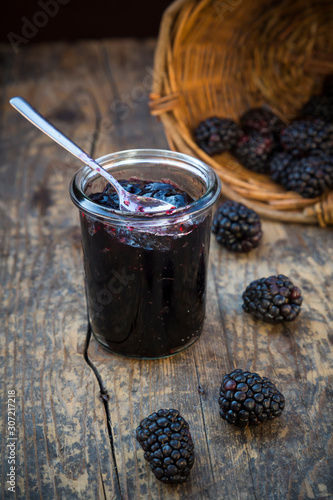 Basket of blackberries (Rubus sectio Rubus) and preserving jar of blackberriy jelly on wooden table photo