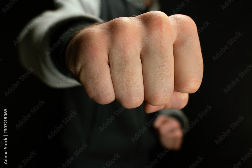 Attacker from the dark criminal waves his fist, close-up