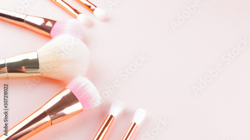 Makeup brushes on pink background. Set of golden makeup brushes, concept. Woman beauty accessory in pastel colors. Copy space. Widescreen
