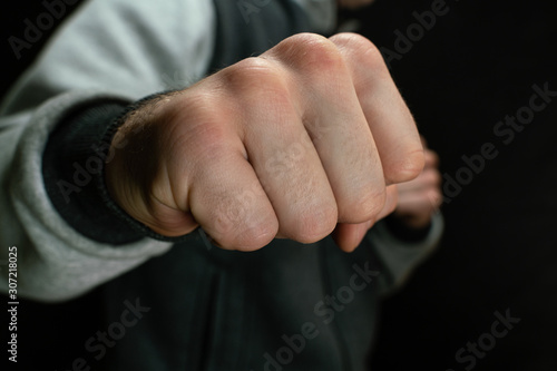 Attacker from the dark criminal waves his fist, close-up