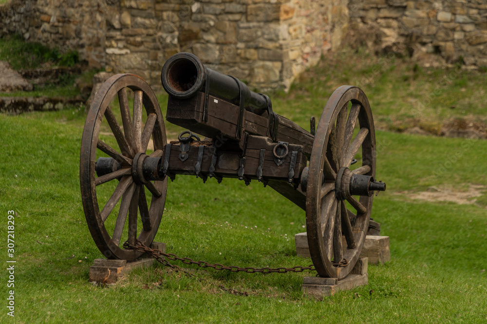 Cannon on green grass with stone wall in Brumov castle