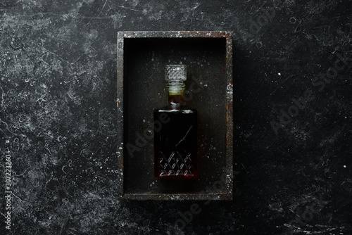 Brandy whiskey in a bottle on a black stone table. Top view. Free space for your text.