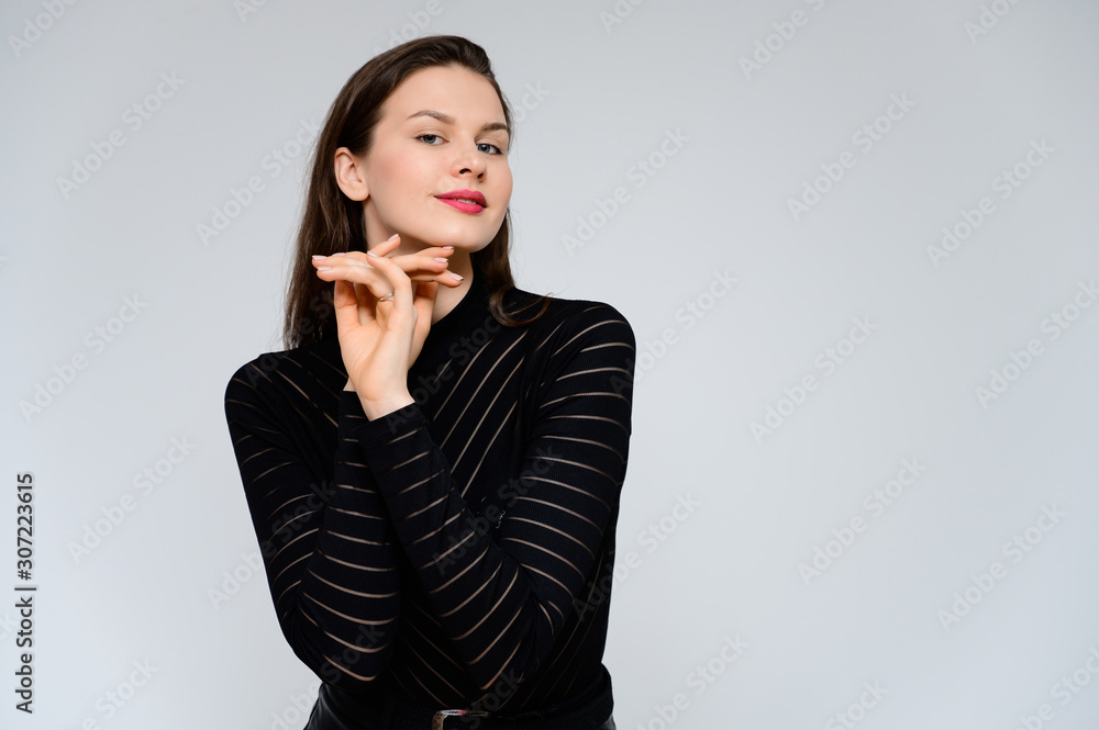 Concept adult girl on a white background. Large photo of a pretty brunette girl in a black sweater smiling and showing different emotions in different poses right in front of the camera. Concept adult girl on a white background. Large photo of a pretty brunette girl in a black sweater smiling and showing different emotions in different poses right in front of the camera.