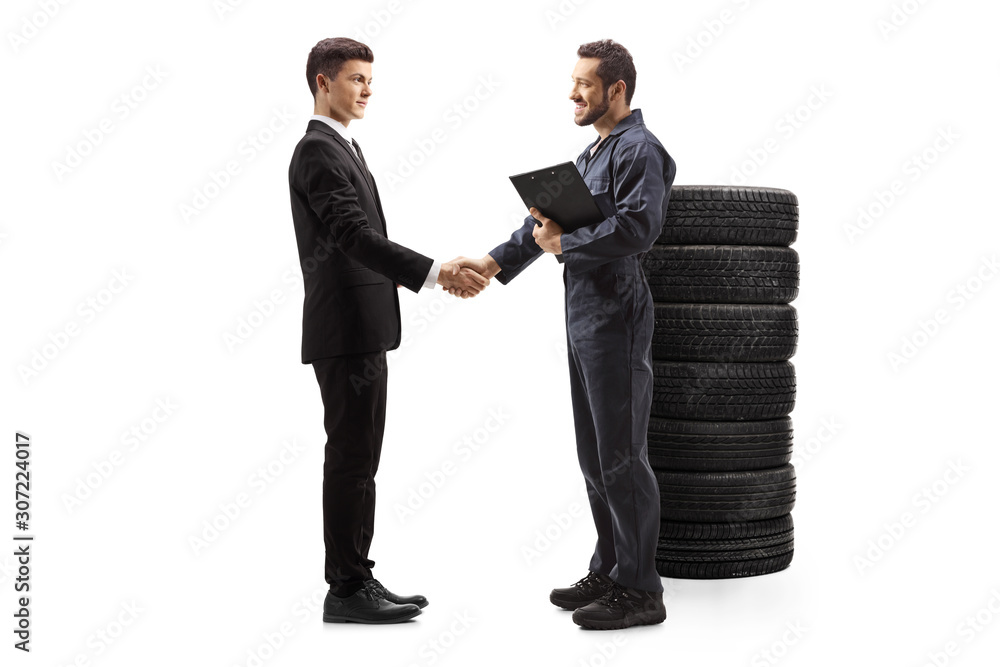 Auto mechanic shaking hand with a young guy in a suit Auto mechanic shaking hand with a young guy in a suit