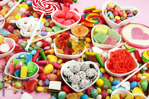 candies with jelly and sugar. colorful array of different childs sweets and treats on pink background