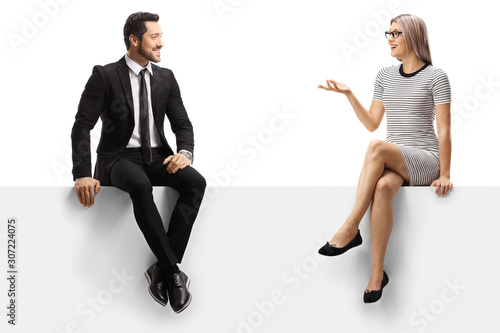 Young businessman and a young lady having a conversation while sitting on a panel