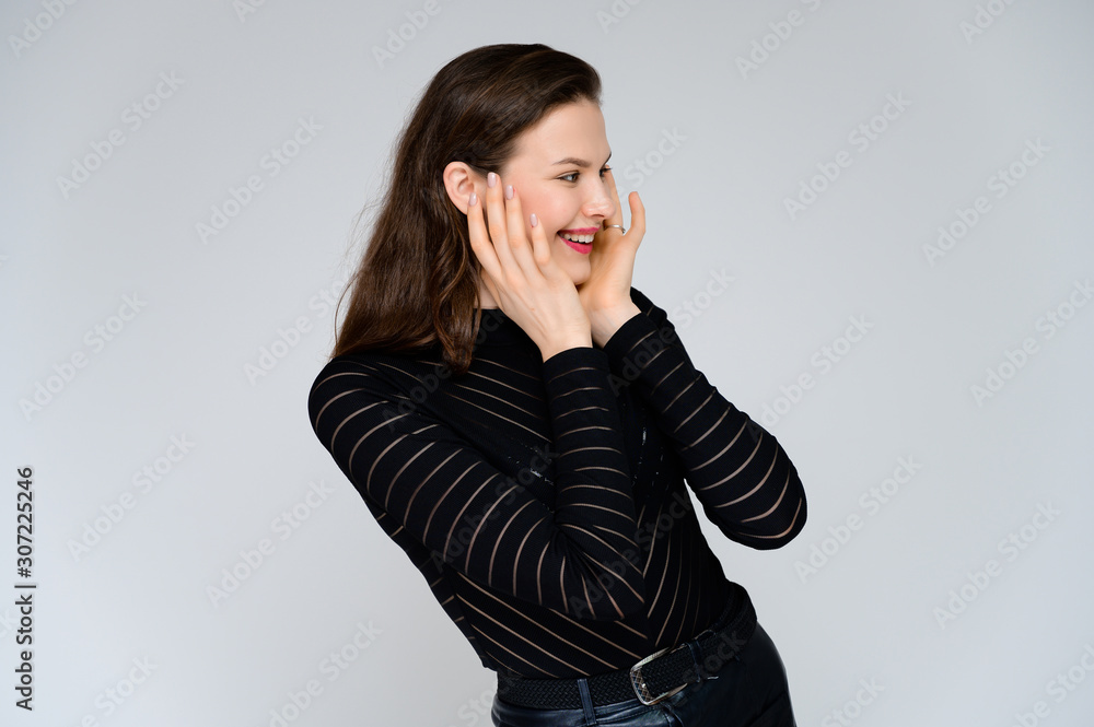 Concept adult girl on a white background. Large photo of a pretty brunette girl in a black sweater smiling and showing different emotions in different poses right in front of the camera. Concept adult girl on a white background. Large photo of a pretty brunette girl in a black sweater smiling and showing different emotions in different poses right in front of the camera.