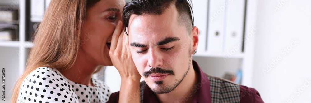 Obraz premium Woman gossip whispers in the ear of news to a man