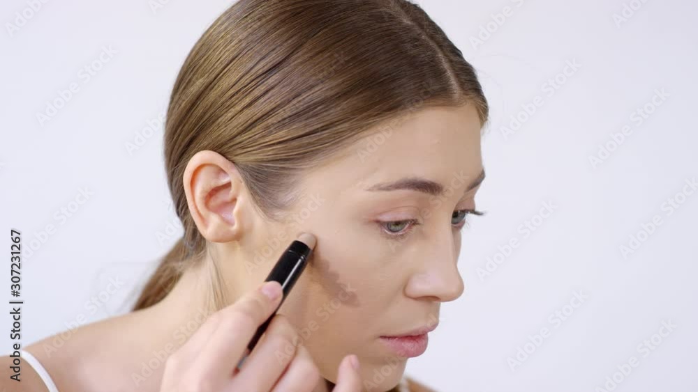 Close up shot of beautiful young woman contouring her face Close up shot of beautiful young woman contouring her face