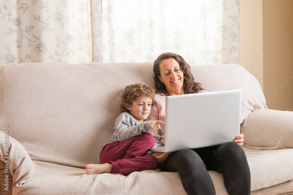 Child and woman sitting on a sofa watching a laptop. Child and woman sitting on a sofa watching a laptop.
