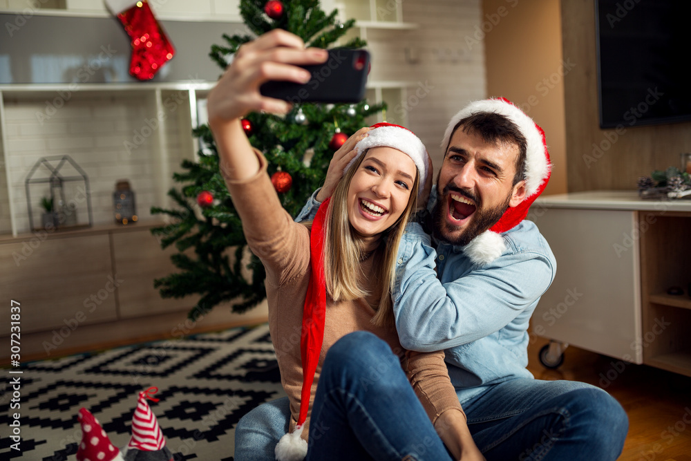 Cute young love couple make selfie with phone at Christmas time Cute young love couple make selfie with phone at Christmas time