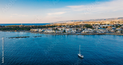 Aerial view of Paphos embankment or promenade, view from water with white yacht on foreground. Famous Cyprus mediterranean resort. Travel concept, drone photo.