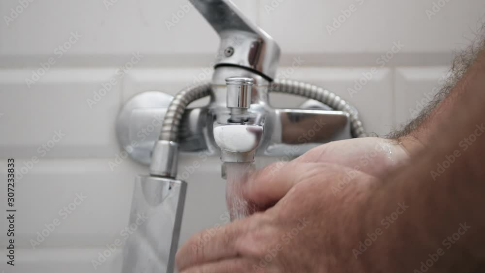 Man Opening Bathroom Faucet and Cleaning His Hands with Water Man Opening Bathroom Faucet and Cleaning His Hands with Water