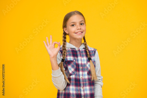 Just excellent. Happy international childrens day. Little girl yellow background. Good mood concept. Positive vibes. Sincere emotions. Cute braided girl. Kid long hair. Small girl checkered shirt
