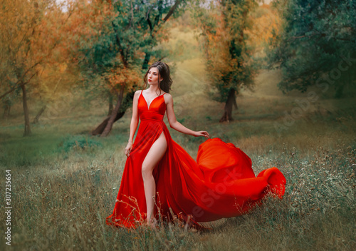 Foto Glamorous brunette woman in red scarlett dress very high sexy slit on her leg