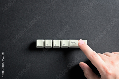 Computer keyboard keys with 2020 enter written using the white buttons on a dark background. Holiday technology concept. New year 2020 card.
