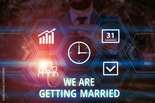 Word writing text We Are Getting Married. Business photo showcasing Engagement Wedding preparation Loving couple Male human wear formal work suit presenting presentation using smart device photo