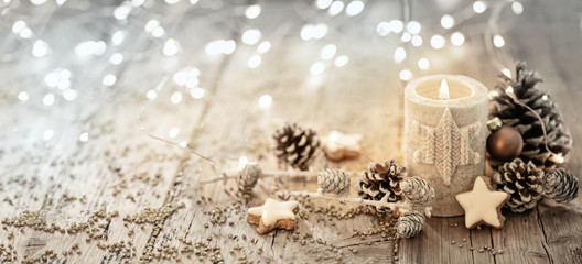 White Christmas candle on rustic wooden boards -  Decoration with natural elements, twigs, pine cones and cookies  -  First Advent Sunday , Advent banner, panorama with magic bokeh lihgts