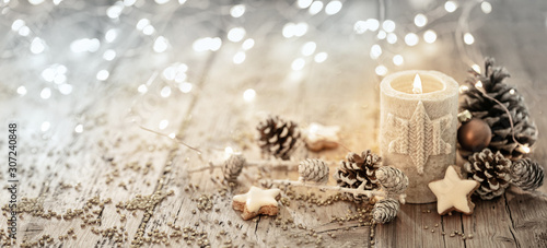 White Christmas candle on rustic wooden boards -  Decoration with natural elements, twigs, pine cones and cookies  -  First Advent Sunday , Advent banner, panorama with magic bokeh lihgts