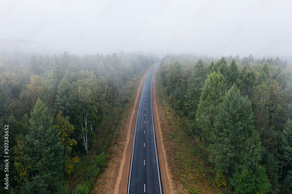 Empty highway in foggy siberian forest, aerial view. Moody travel background. Road trip in Buryatia, Siberia, Russia