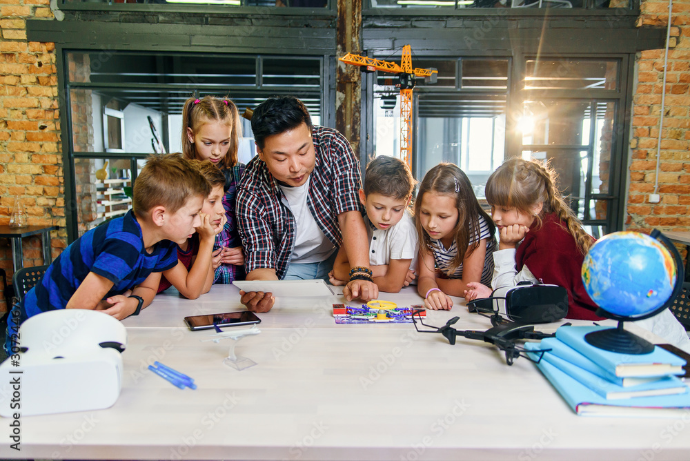 Creative school children with young asian teacher study an electronic constructor with fan and turn on flashlight. Creative pupils with teacher working on the tech project at school. Creative school children with young asian teacher study an electronic constructor with fan and turn on flashlight. Creative pupils with teacher working on the tech project at school.