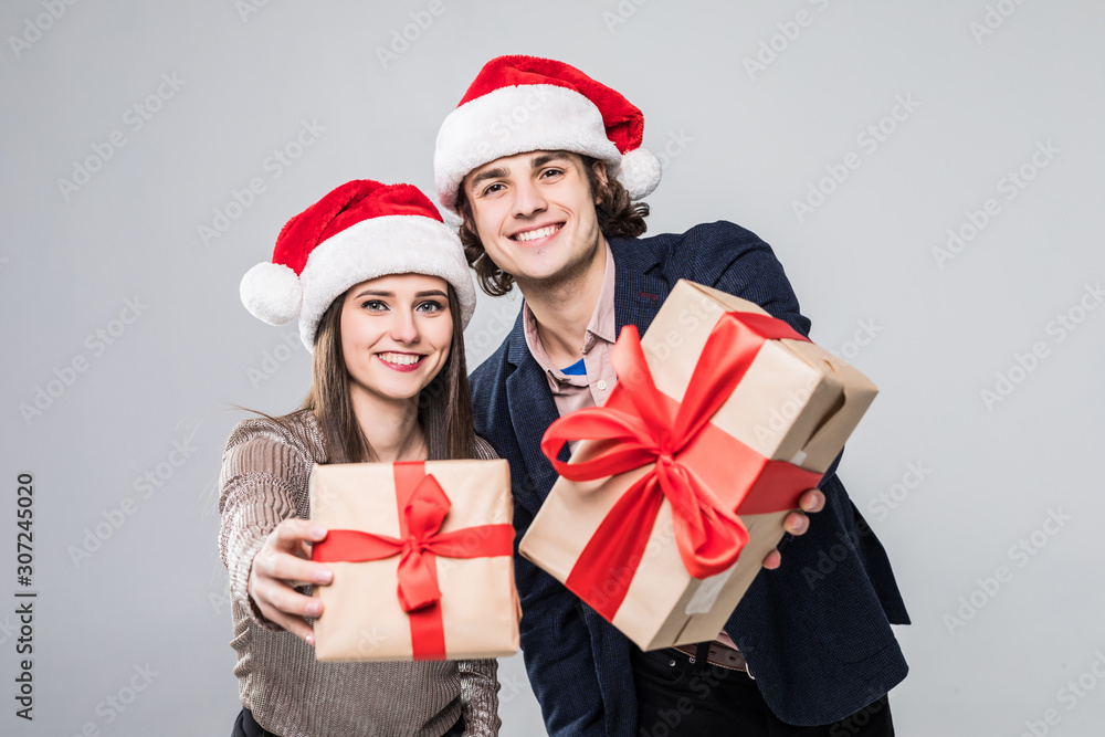 Christmas holiday. Young couple happy young with gift in hand, isolated over white background wear santa hats. Christmas holiday. Young couple happy young with gift in hand, isolated over white background wear santa hats.