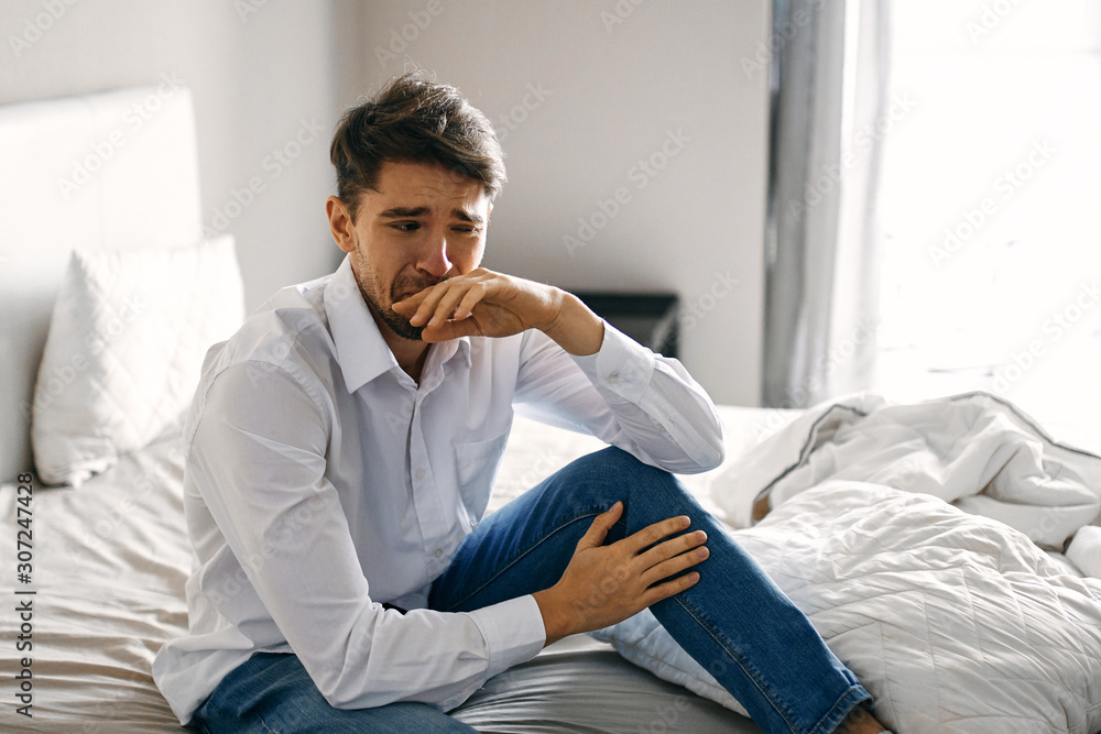 young man sitting on sofa and talking on cell phone young man sitting on sofa and talking on cell phone