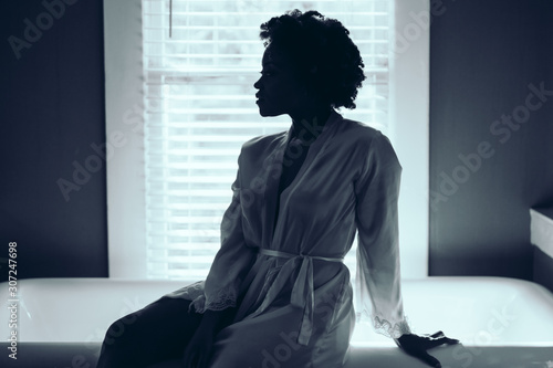 Woman wearing robe and sitting on edge of bathub