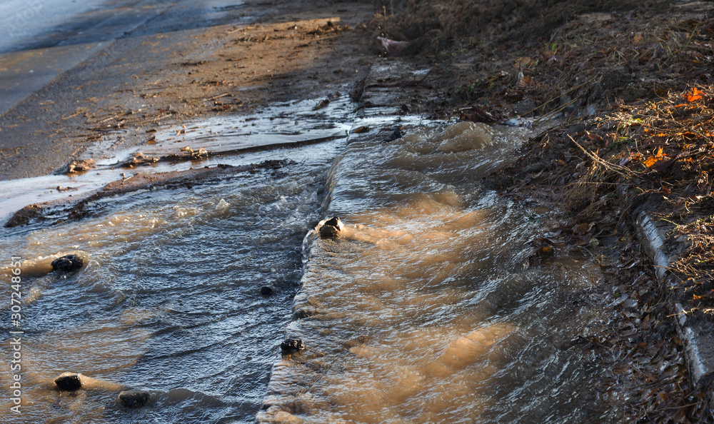 Emergency Sewerage. Water flows down the sidewalk from a ruptured underground sewer pipe. The