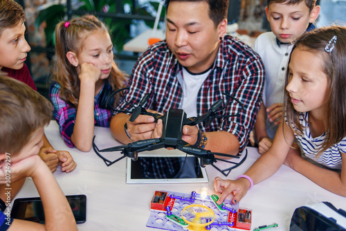 Young creative teacher explains for students the principle of quadcopter work. photo