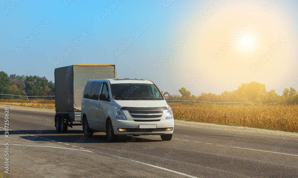 Obraz premium Minivan with trailer. Moving along a suburban highway