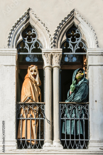 Venice Carnival, mask in mullioned window in the venetian style on a historical building in Venice, Italy