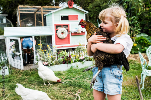 Girl holding chicken in garden photo