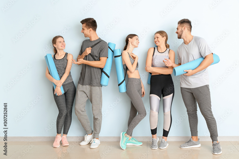 Fototapeta premium Group of people with yoga mats near color wall