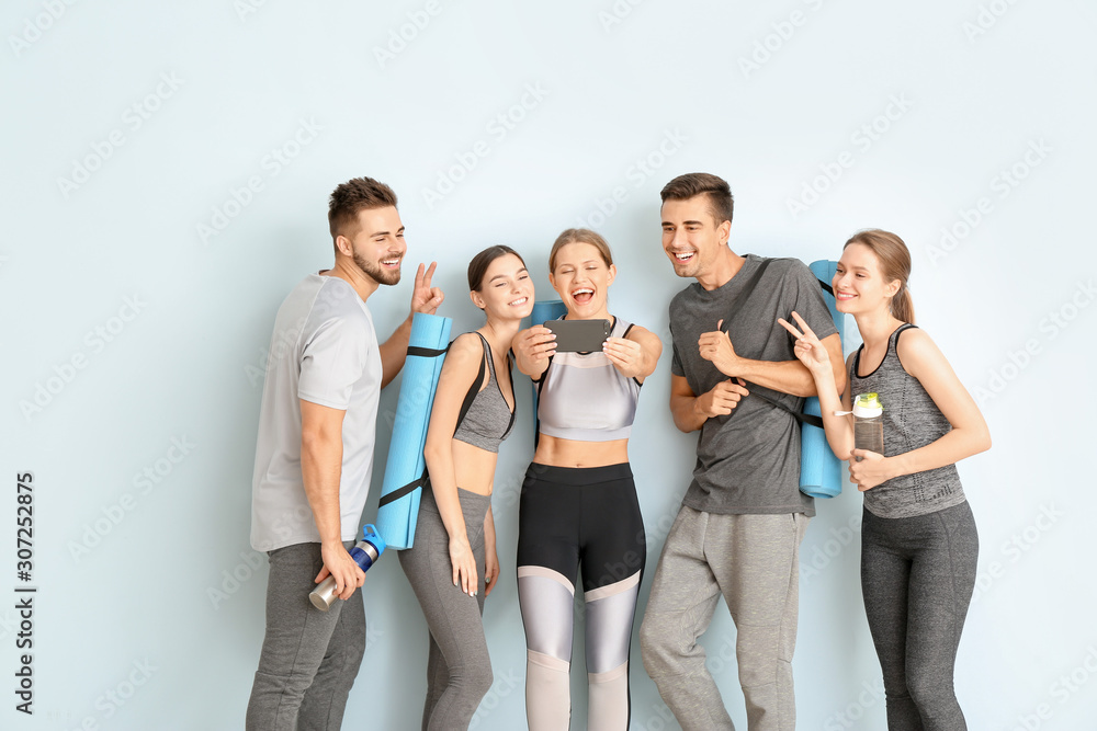 Fototapeta premium Group of people with yoga mats taking selfie near color wall