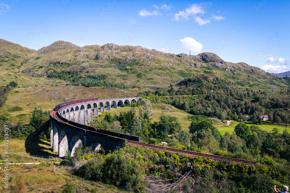 View on famous Glenfinnan viaduct from Harry Potter movies with red Jacobi train, Scotland