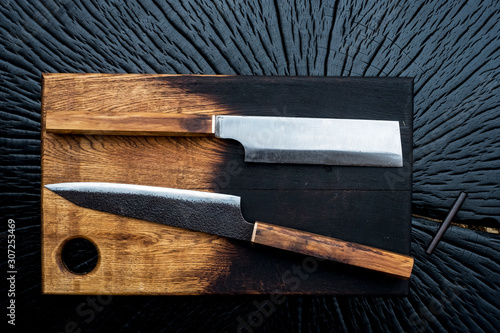 High angle close up of two handmade knives on wooden cutting board. photo