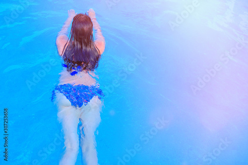Girl in swimsuit on the water in the blue pool, copy space