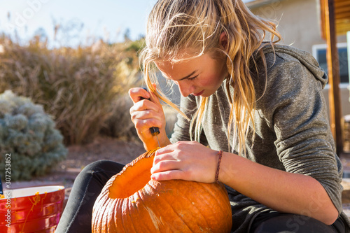 Teenage girl carving pumpkin for Halloween outdoors photo